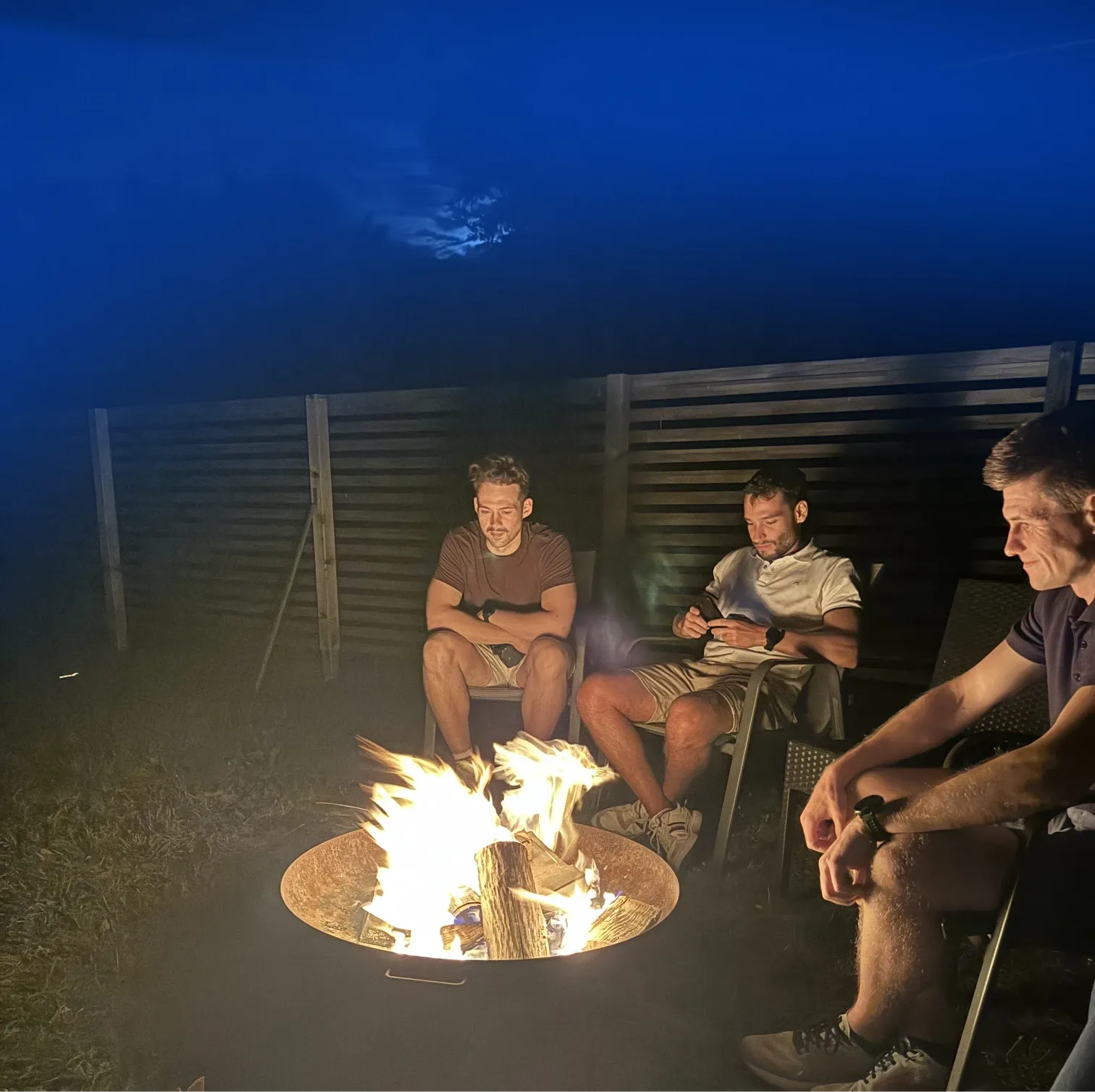 dnl team members sitting around a firepit in the evening