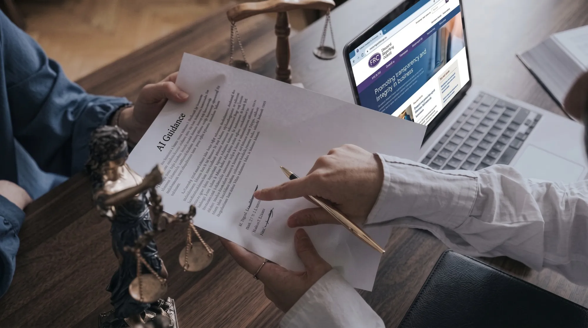 Two people at a desk reviewing a printed document headed "AI Guidance", one pointing at the signature line, with an open laptop and a set of brass scales beside them.